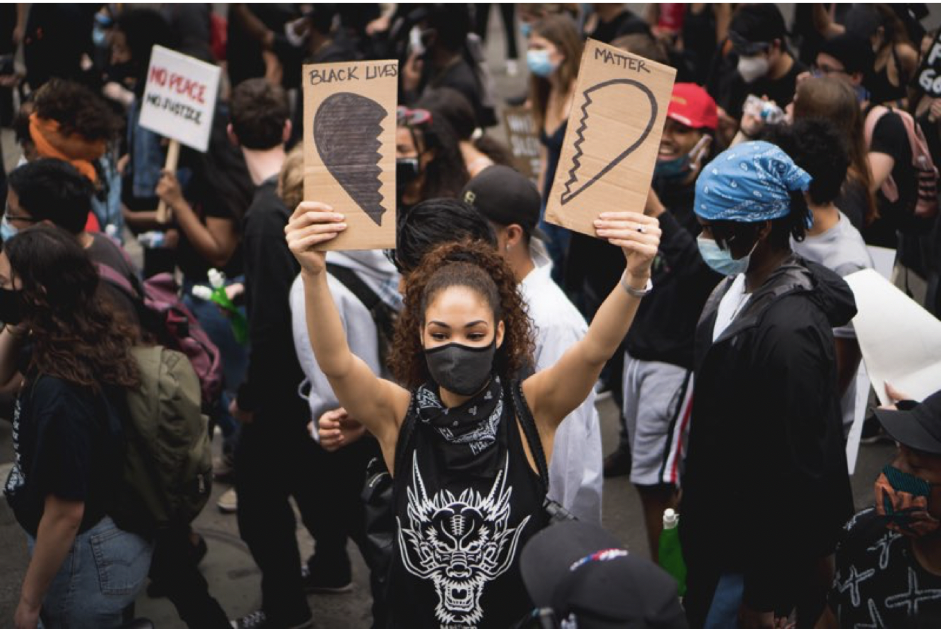 Woman at protest with sign saying Black Lives Matter with an image of a broken heart.