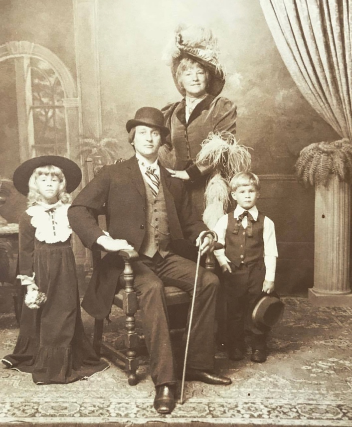 Mother, Father, two children in sepia toned photo with old fashioned clothes.